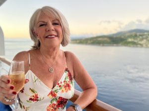 Oceania Cruises, Carol enjoys a glass of champagne from the deck of our Penthouse Suite.