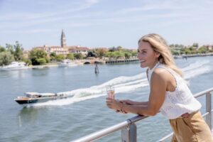 Guest enjoying the view from a Uniworld river cruise ship while sailing through the Venice lagoon during a luxury Cruise & Tour itinerary in Italy.