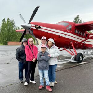 Three generations of our family standing in front of a red bush plane before our Tauck Bridges Call of the Wild flightseeing adventure in Alaska.